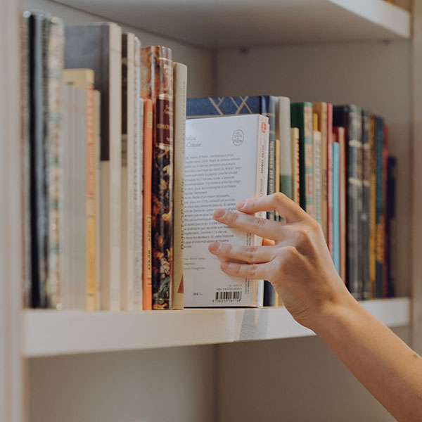 Photo of a hand touching books on a bookshelf 2